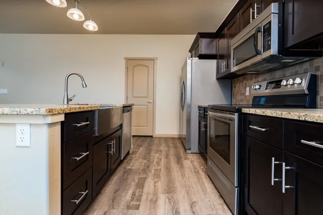 a kitchen with stainless steel appliances granite countertop a stove a sink and a refrigerator