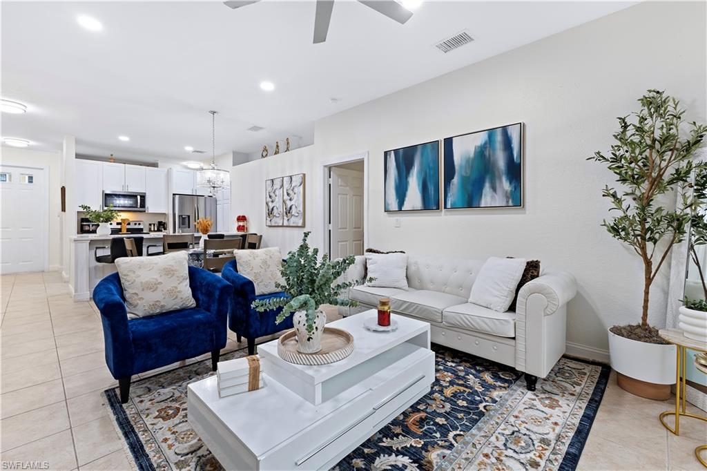 7542 Bristol Circle Naples, FL 34120 - Photo 9 of 26 Tiled living room with ceiling fan with notable chandelier