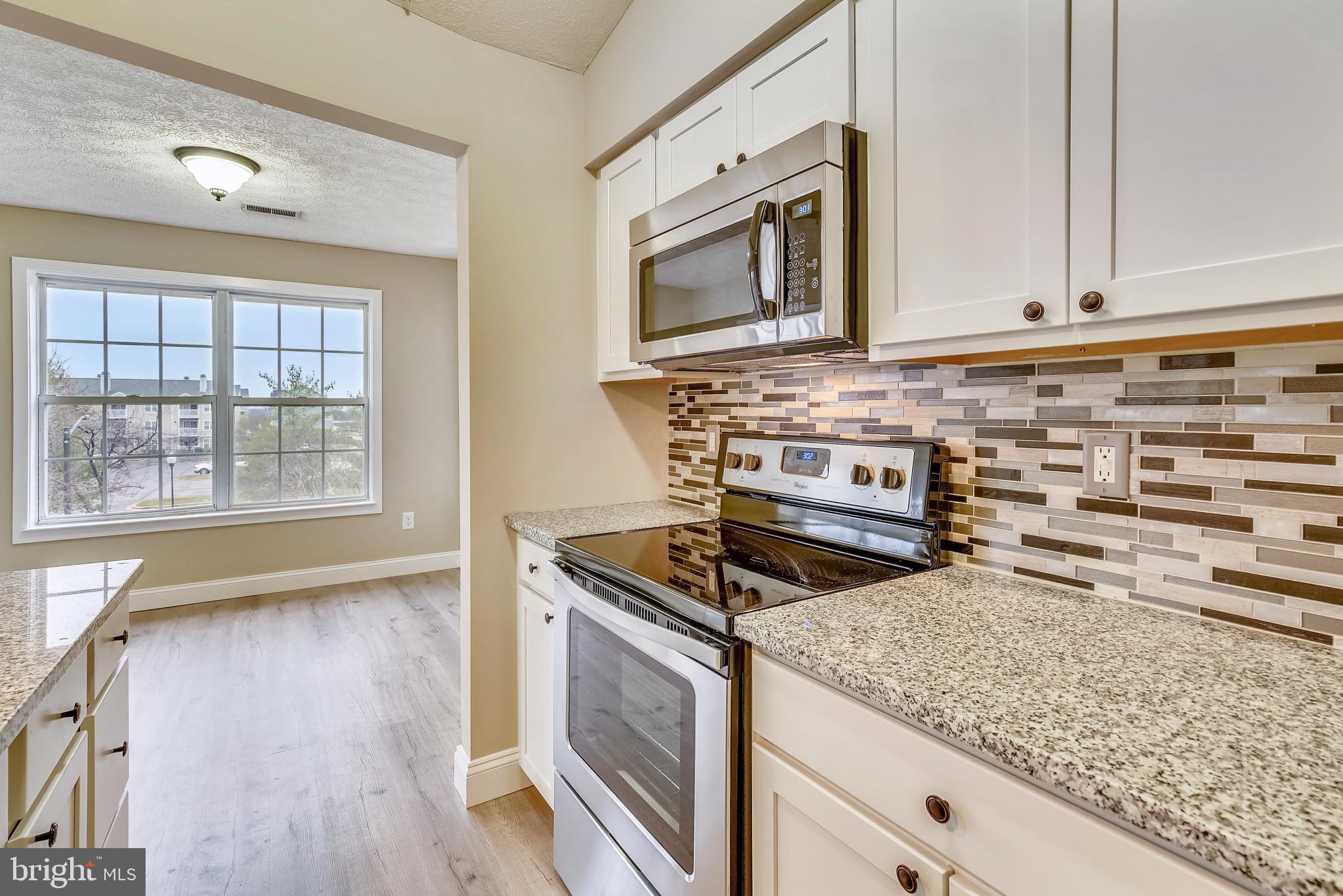 2408 Forest Edge Court, Unit 303 Odenton, MD 21113 - Photo 11 of 46 a kitchen with stainless steel appliances granite countertop a stove a microwave and a sink