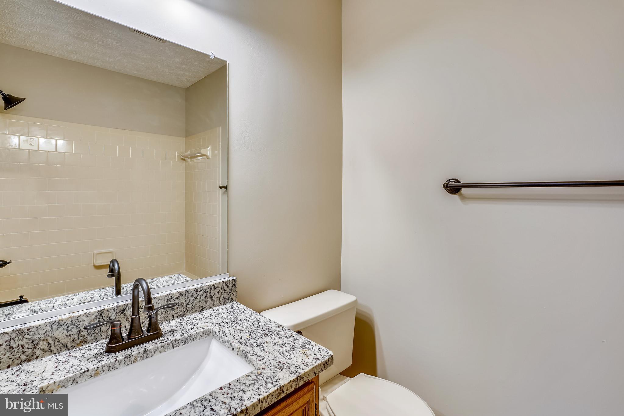 2408 Forest Edge Court, Unit 303 Odenton, MD 21113 - Photo 19 of 46 a bathroom with a granite countertop sink a toilet and a mirror