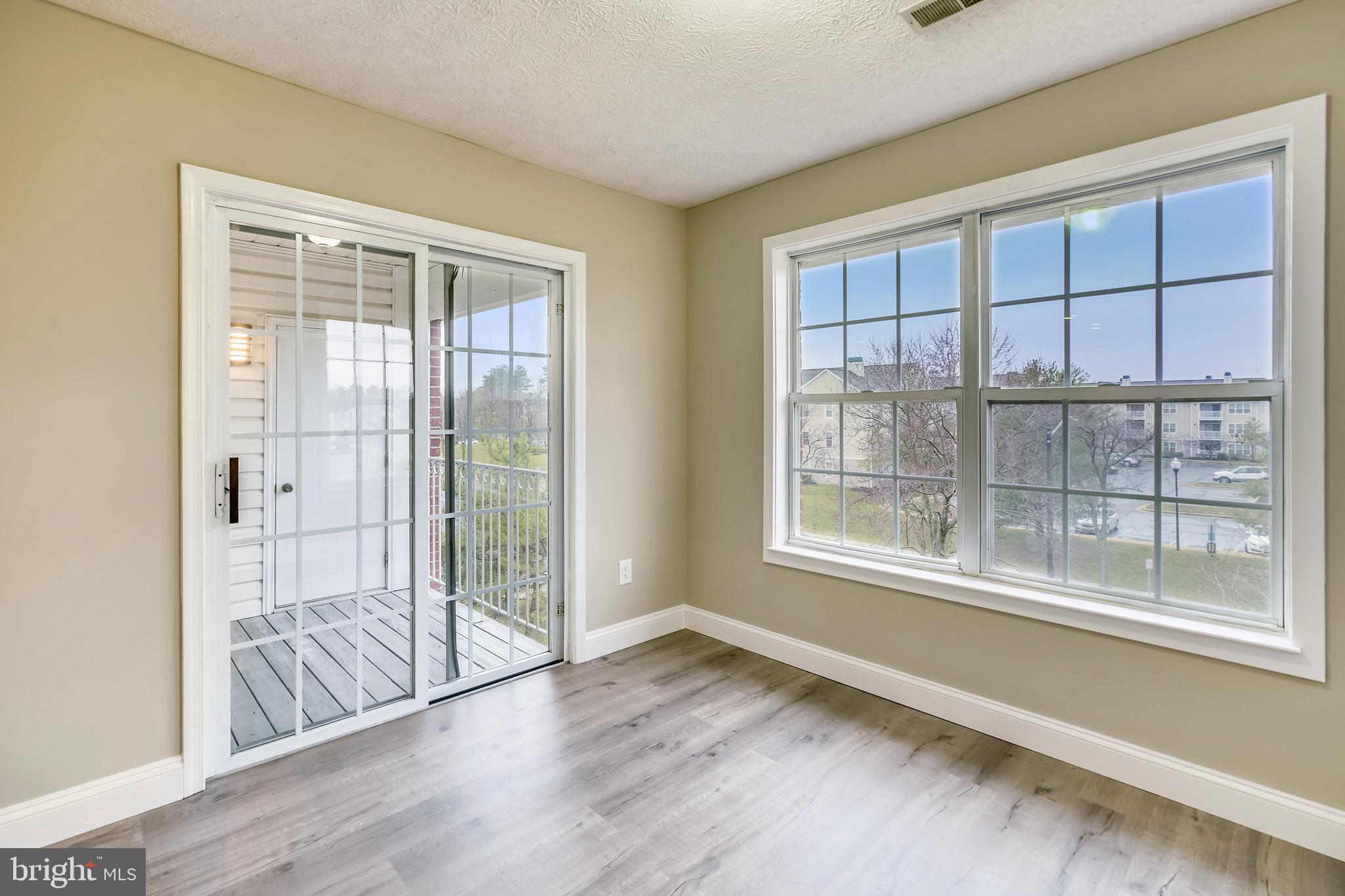 2408 Forest Edge Court, Unit 303 Odenton, MD 21113 - Photo 8 of 46 a view of an empty room with wooden floor and a window