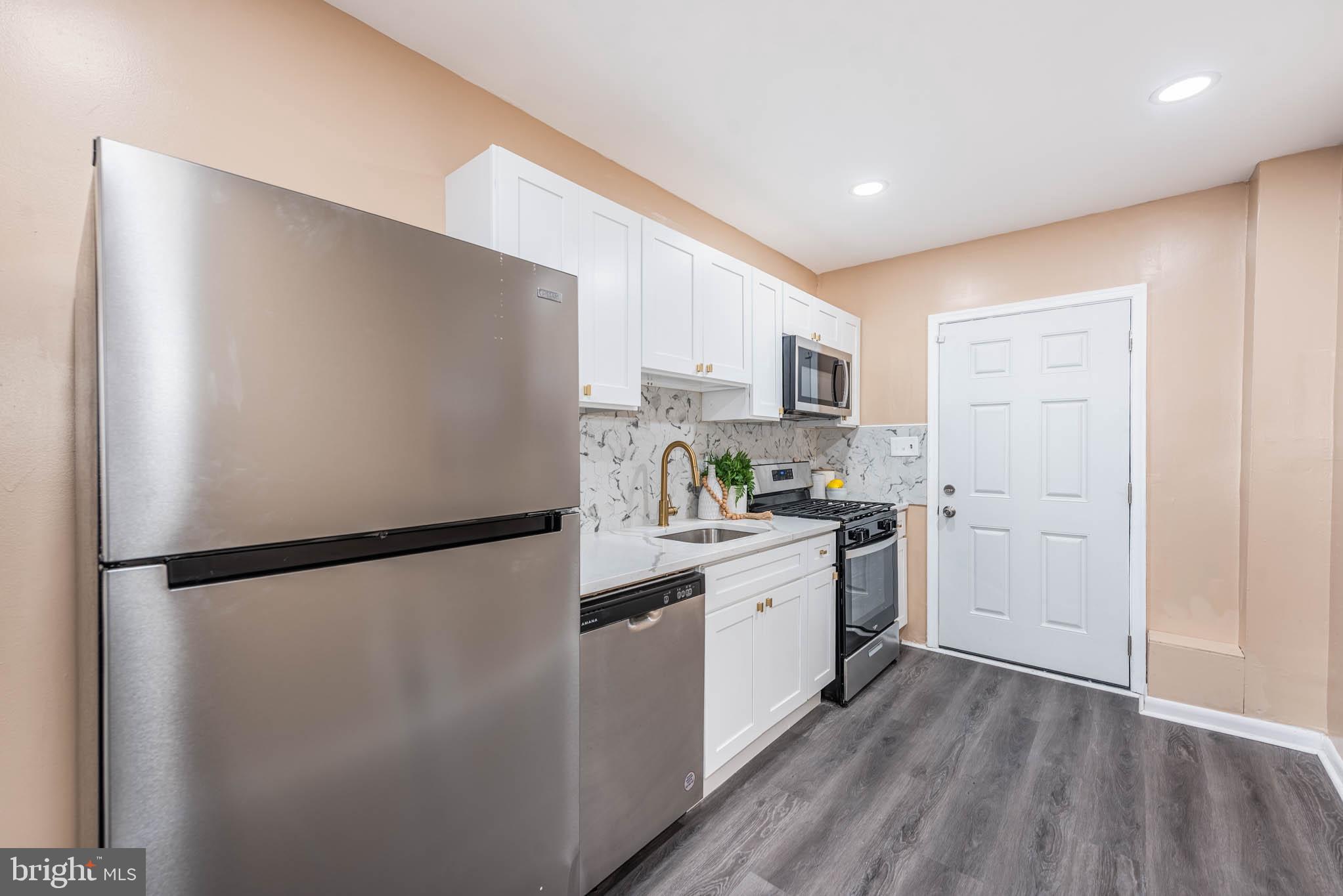 1705 East 25th Street Baltimore, MD 21213 - Photo 7 of 21 a kitchen with a refrigerator a stove top oven and white walls