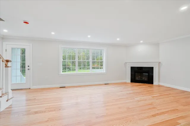 a view of an empty room with window and wooden floor