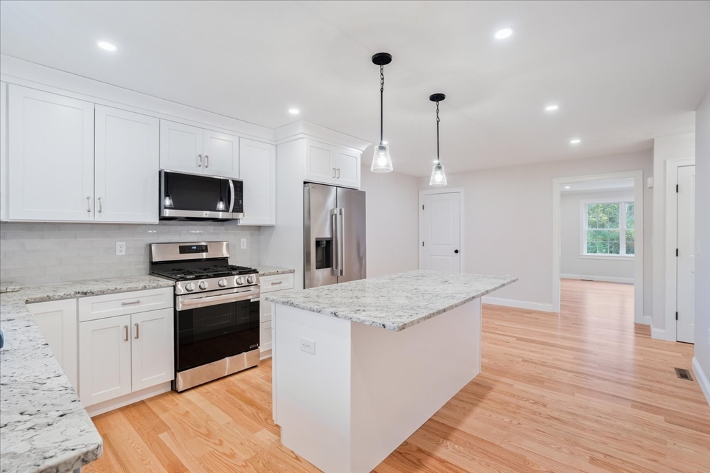 515 Mendon Road, Unit 515 Attleboro, MA 02703 - Photo 9 of 33 a large kitchen with stainless steel appliances kitchen island granite countertop a stove a sink a refrigerator and a wooden floor