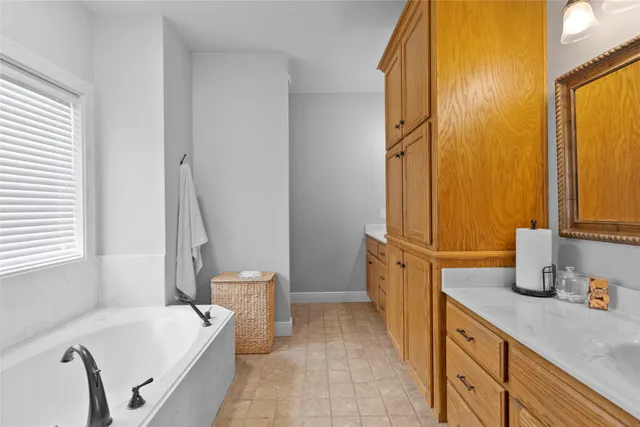 a spacious bathroom with a tub sink and a mirror
