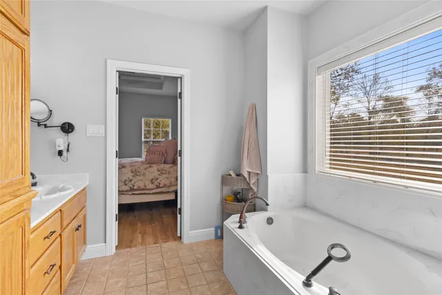 a bathroom with a tub a sink and a window
