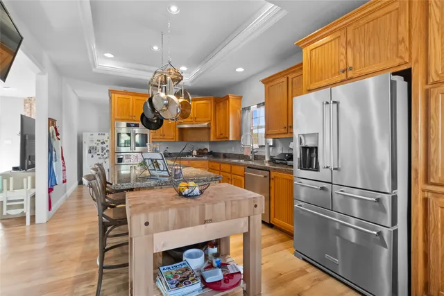 a kitchen with stainless steel appliances granite countertop a refrigerator a oven a sink dishwasher and white cabinets with wooden floor