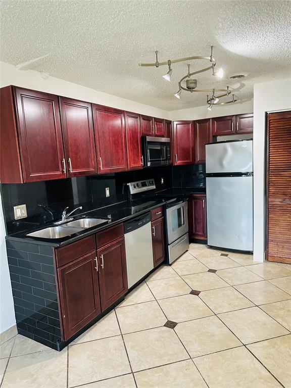 10046 Winding Lake Road, Unit 203 Sunrise, FL 33351 - Photo 1 of 31 a kitchen with kitchen island granite countertop a sink a counter top space cabinets and stainless steel appliances