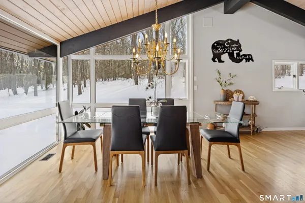a dining room with wooden floor a glass table and chairs