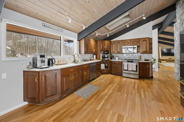 a large kitchen with stainless steel appliances granite countertop a stove and a wooden floors