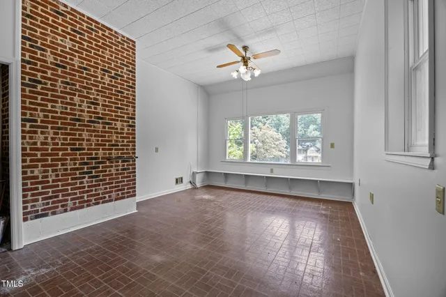 an empty room with windows and ceiling fan