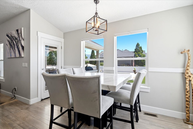 2973 West Red Sand Rd Haven Ogden, UT 84401 - Photo 15 of 30 Dining area featuring wood-finish flooring, two large windows, a glass-paned exterior door, and a geometric pendant light fixture