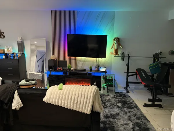 a living room with furniture a flat screen tv and gym equipment