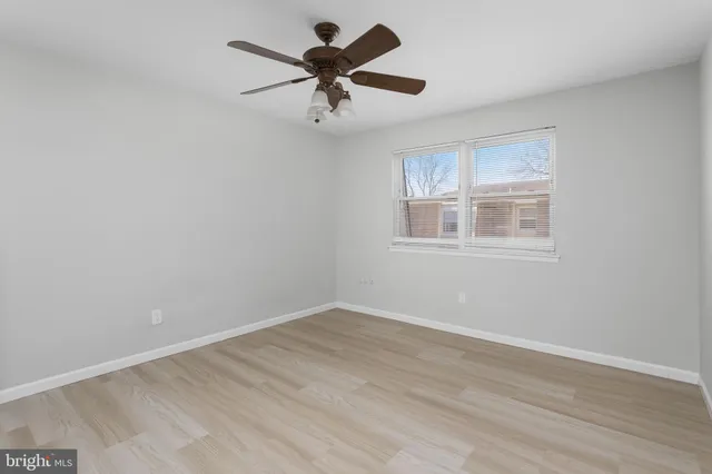 a view of empty room with wooden floor and ceiling fan