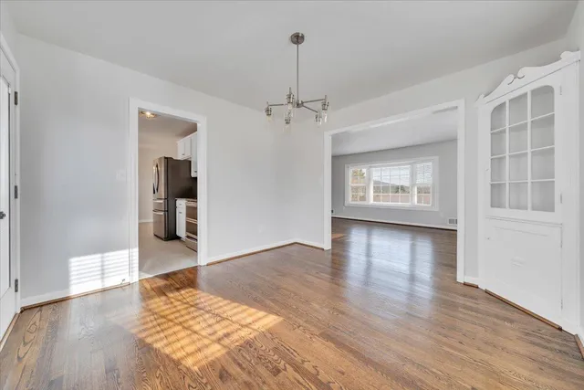 a view of an empty room with window and wooden floor