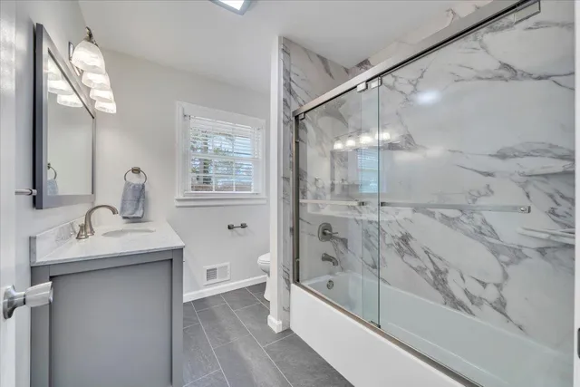 a bathroom with a granite countertop sink a toilet and shower
