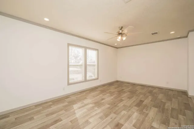 a view of an empty room with wooden floor and a window