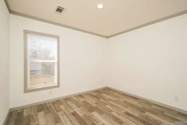 an empty room with windows and fan