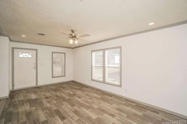 an empty room with windows and ceiling fan