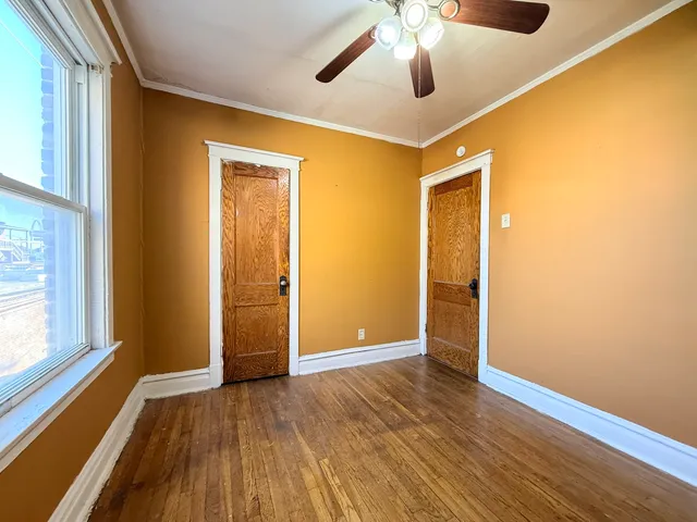 a view of empty room with wooden floor and fan