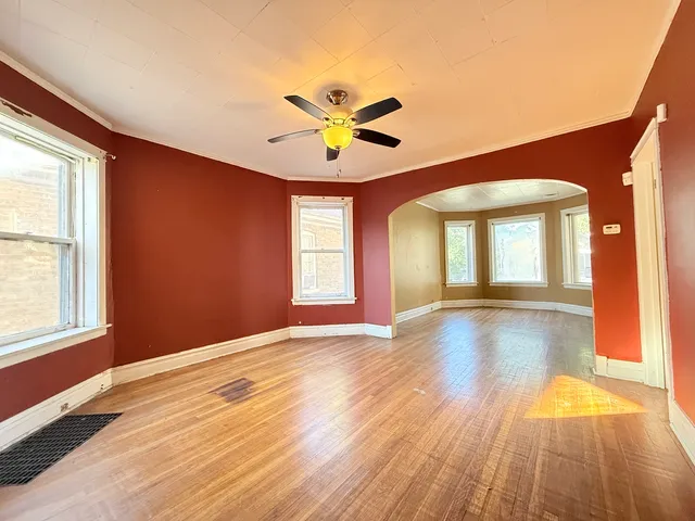 a view of an empty room with window and wooden floor