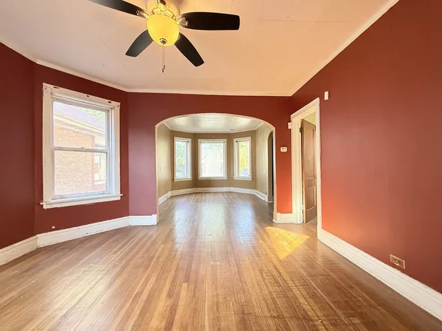 a view of empty room with wooden floor and fan