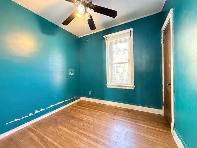 an empty room with wooden floor closet and windows