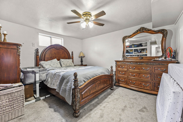 7609 Mountain View Road Lake Point, UT 84074 - Photo 12 of 16 Bedroom featuring light carpet, a ceiling fan, and a textured ceiling