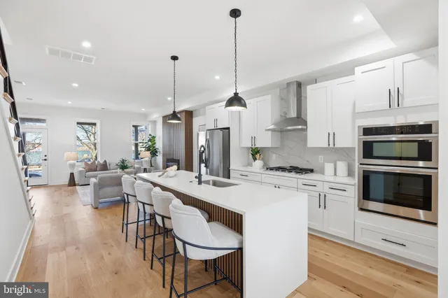 a kitchen with stainless steel appliances kitchen island granite countertop a stove a sink a oven a dining table and chairs with wooden floor