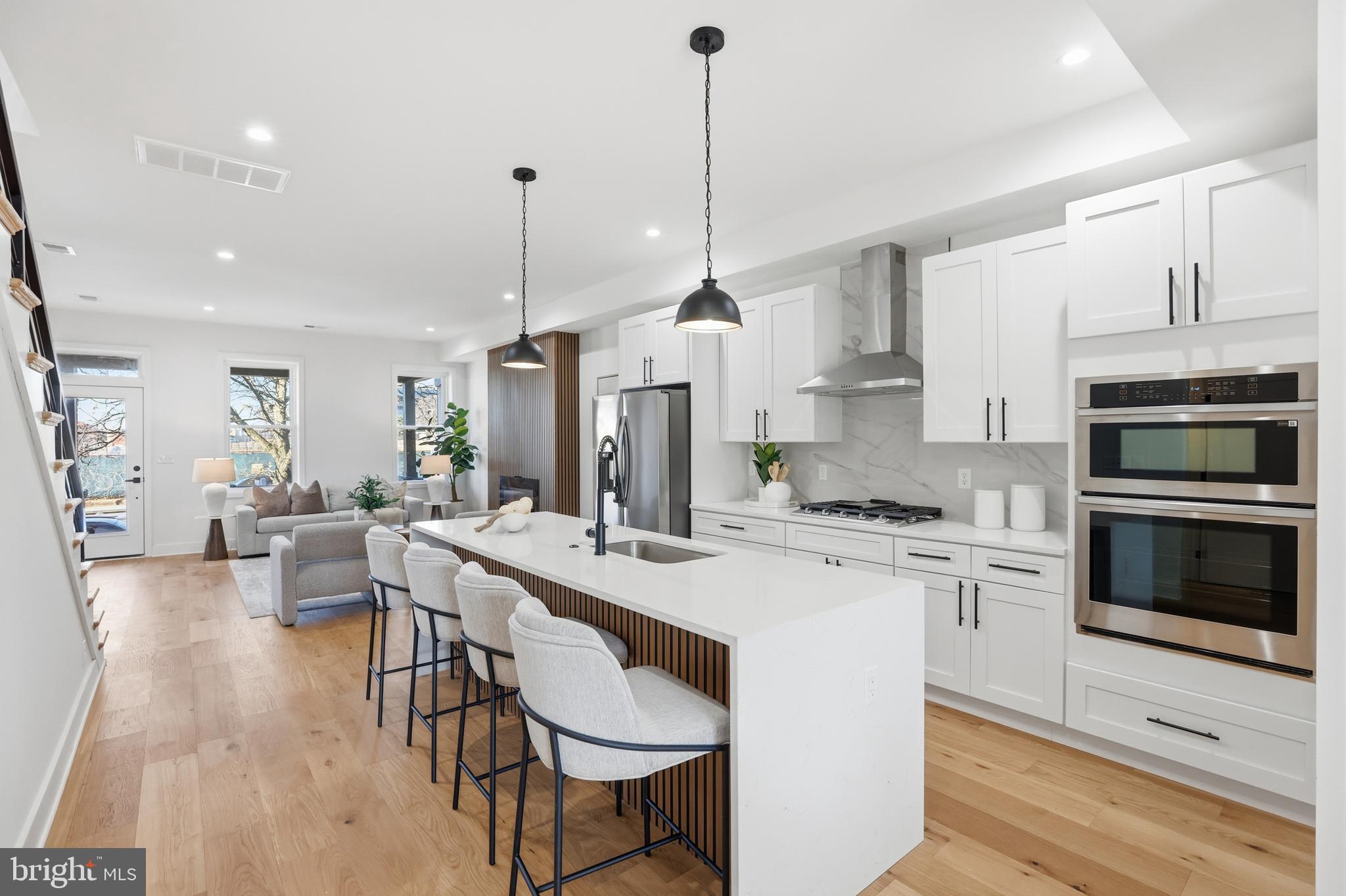 a kitchen with stainless steel appliances kitchen island granite countertop a stove a sink a oven a dining table and chairs with wooden floor