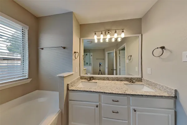 a bathroom with a granite countertop sink a large mirror and a bathtub