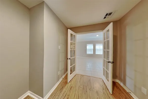 a view of a hallway with wooden floor and a bathroom