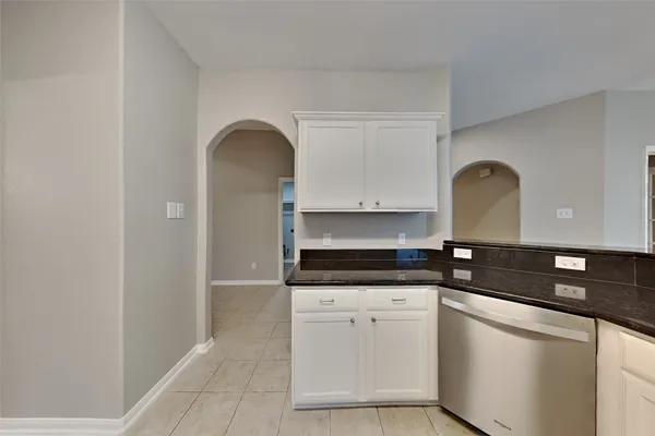 a kitchen with granite countertop white cabinets and black appliances