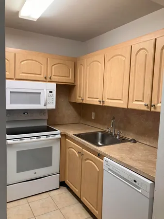 a kitchen with granite countertop white cabinets sink and stainless steel appliances