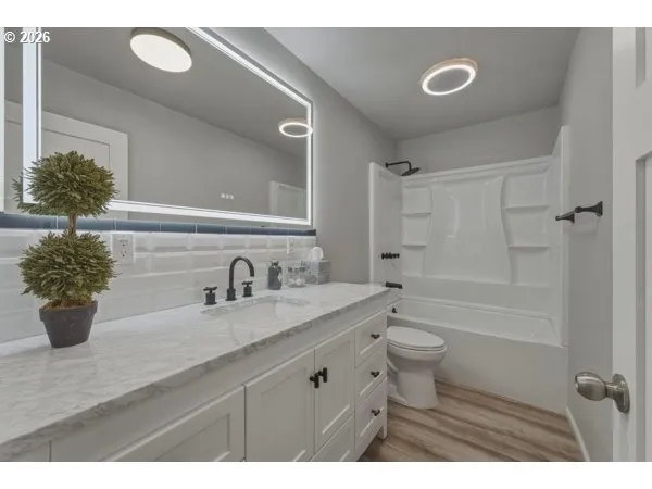 a bathroom with a granite countertop sink a toilet and shower