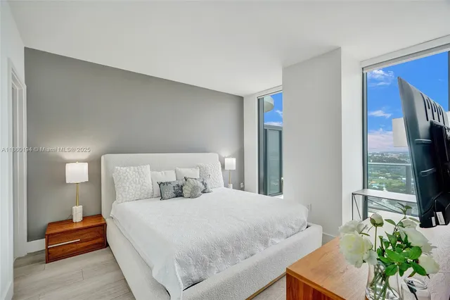 a bedroom with a bed a flat screen tv and a potted plant