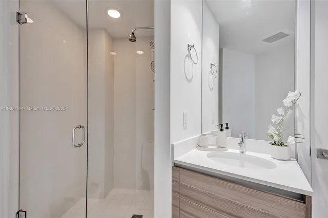 a bathroom with a sink shower and a mirror