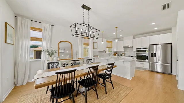 a kitchen with stainless steel appliances kitchen island granite countertop a dining table chairs refrigerator and sink