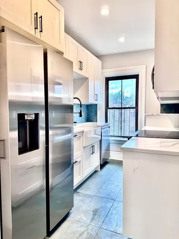 a kitchen with granite countertop white cabinets and stainless steel appliances