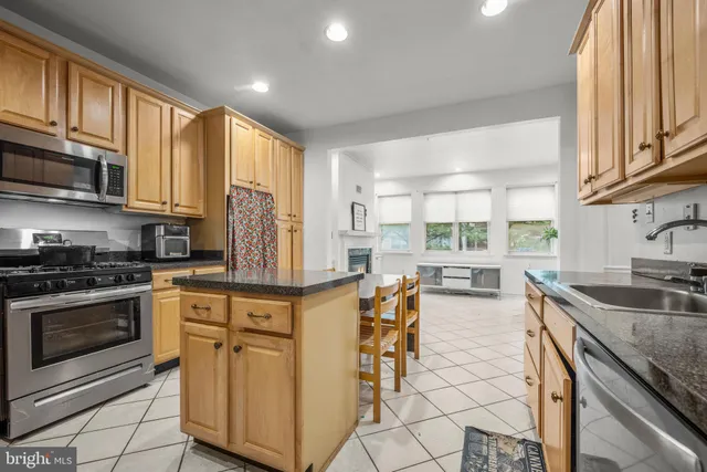 a kitchen with stainless steel appliances granite countertop a stove a sink dishwasher a microwave oven and a dining table with wooden cabinet