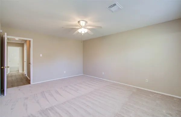 a view of an empty room and chandelier fan