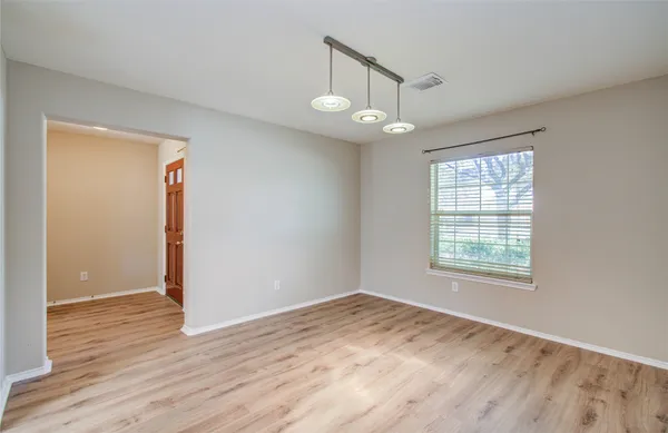an empty room with wooden floor chandelier and window