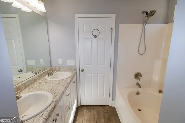 a bathroom with a granite countertop tub sink and mirror