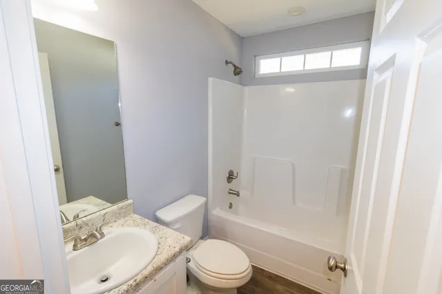 a white toilet sitting next to a bathroom sink and a mirror