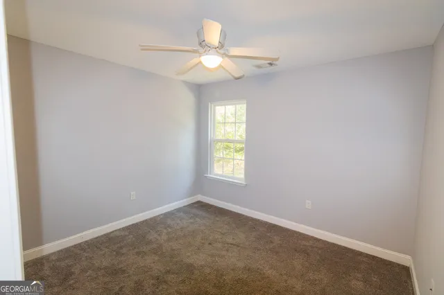 an empty room with a window and a fan
