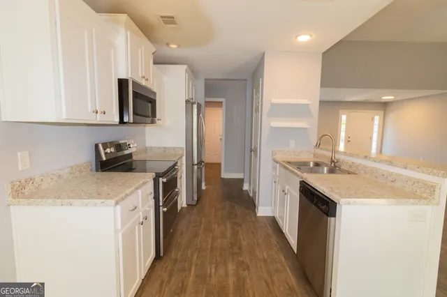 a kitchen with granite countertop a sink a stove top oven a counter space and cabinets