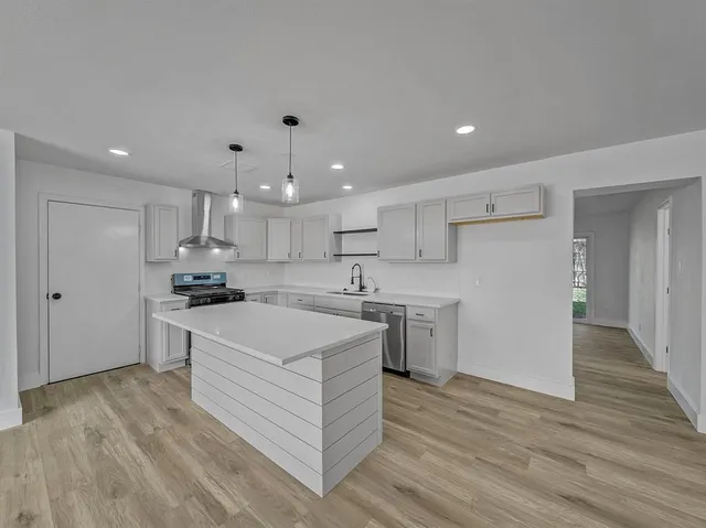 a large white kitchen with a stove a sink dishwasher and a refrigerator