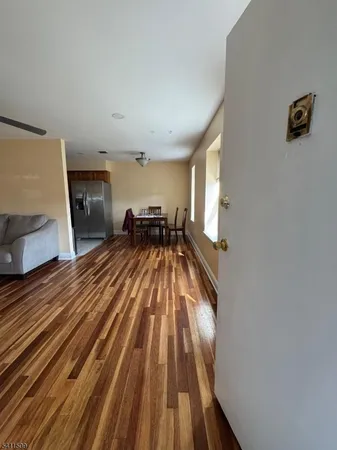 a view of kitchen and empty room with wooden floor
