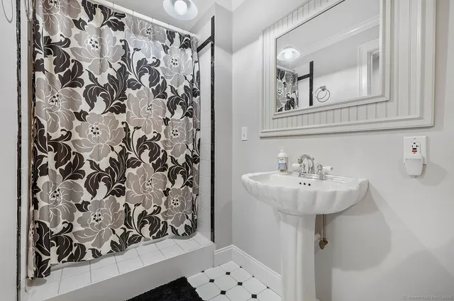 a bathroom with a sink and mirror with bathtub