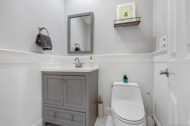 a bathroom with a toilet sink vanity and mirror